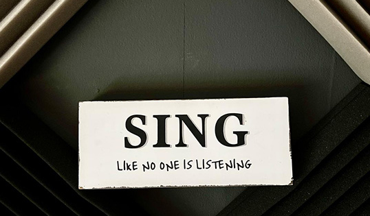 Motiverend bordje in de zangstudio met de tekst ‘Sing like no one is listening’, passend bij stembevrijding en vrij leren zingen.